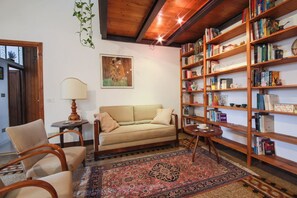 A cozy living room with a sofa, chairs, a bookshelf, and a patterned rug. - Apartments Florence- Sunny Via Romana (Firenze)