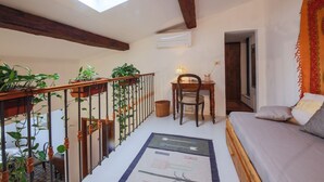 A loft bedroom with a skylight, a desk, a chair, a bed, and potted plants. - Apartments Florence- Sunny Via Romana (Firenze)