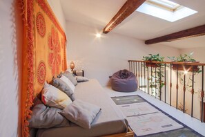 A cozy room with a bed, a bean bag, a patterned rug, and a balcony with plants. - Apartments Florence- Sunny Via Romana (Firenze)