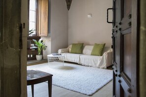Ein Wohnzimmer mit einer Couch, einem Couchtisch, einer Zimmerpflanze und einer Tür.