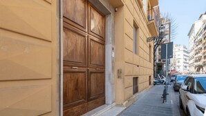 A street view with a large wooden door, parked cars, and buildings in the background. - Apartments Florence- Cherubini Balcony (Firenze)