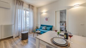 A modern living room with a sofa, a dining table with a wine glass, and a radiator. - Apartments Florence- Cherubini Balcony (Firenze)