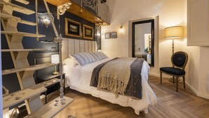 Ein Schlafzimmer mit Bett, Stuhl, Schreibtisch, Treppe und Spiegel.