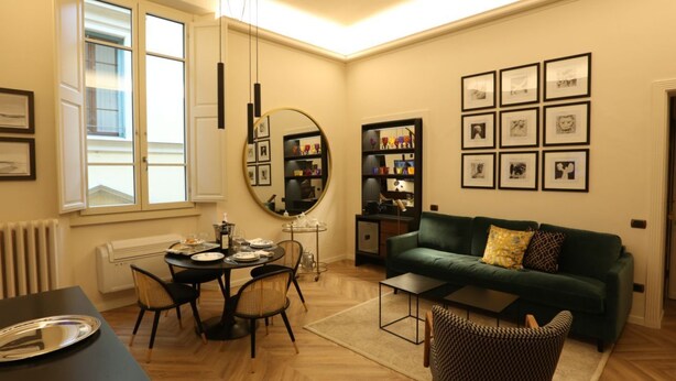Ein modernes Wohnzimmer mit Essbereich, einem grünen Sofa und einer Wand mit gerahmten Bildern.