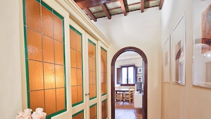 A hallway with a wooden ceiling, a dining area with a table and chairs, and a door with a green frame.