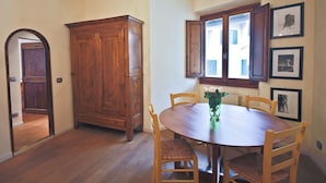A dining room with a wooden table, chairs, a cabinet, and a window with curtains.