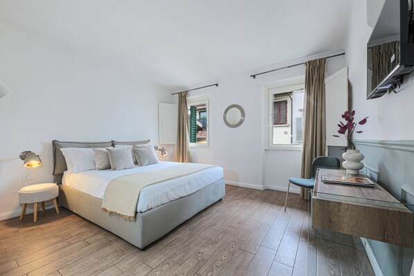 Une chambre à coucher avec un lit, une table de chevet, une lampe, une chaise et une fenêtre avec des rideaux.