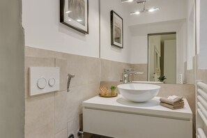 Un baño moderno con un lavamanos grande de color blanco, un espejo y un perchero para toallas.