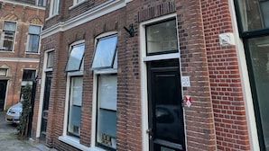 Un edificio in mattoni di due piani con ampie finestre e una porta nera.