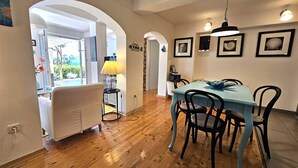 A dining area with a blue table and black chairs, wooden flooring, and a yellow lamp. - Apartment Barbara with sea view (Njivice)