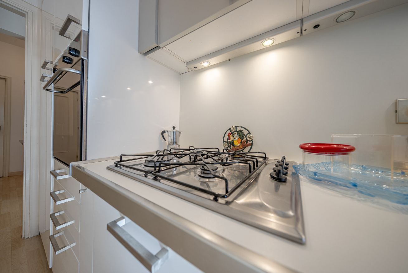 A modern kitchen with a gas stove, stainless steel appliances, and a white countertop.