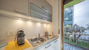 A modern kitchen with a built-in microwave, a sink, and a window overlooking a garden.