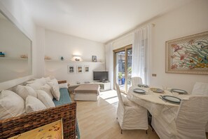 Een moderne woonkamer met een bank, een eettafel voor twee personen, een televisie en een balkon met uitzicht.