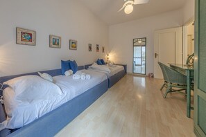 Een kamer met twee bedden, een eethoek en een deur naar een balkon.