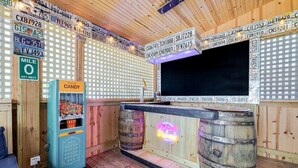 Een bar met houten wanden, een neonreclame, een jukebox en een groot televisiescherm.