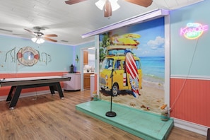 A room with a pool table, a ceiling fan, a neon sign, and a beach-themed mural. - Southern Comfort Bar (Savannah)