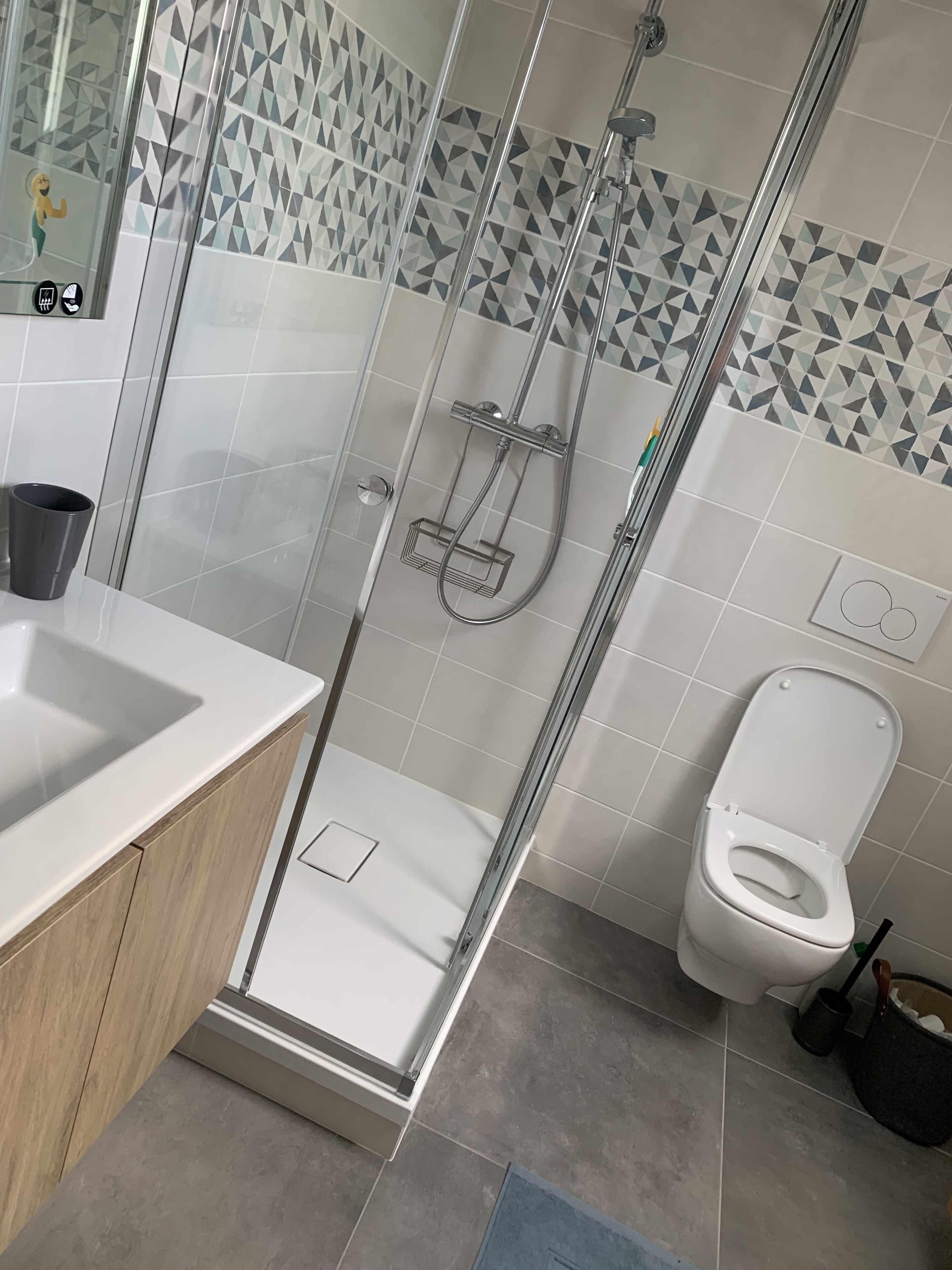 A modern bathroom with a glass-enclosed shower, a white sink, and a toilet.
