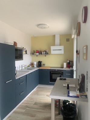 Una cocina moderna con armarios azules, encimera blanca, horno empotrado y microondas.