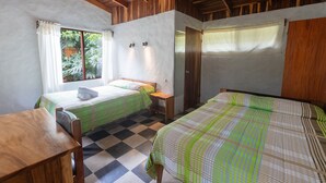 A room with two beds, a wooden table, and a window with curtains. - Elida Lodge Monteverde (Monteverde)
