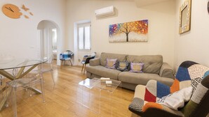 A living room with a sofa, coffee table, and chairs. There is a painting on the wall and an air conditioning unit. - Charming View apartment by Mmega (Firenze)
