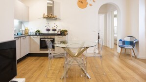 A modern kitchen with a glass dining table, clear chairs, and a clock on the wall. - Charming View apartment by Mmega (Firenze)
