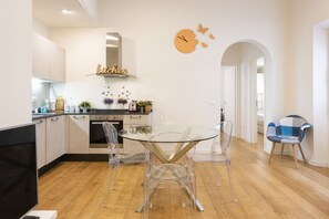A modern kitchen with a glass dining table, clear chairs, and a clock on the wall. - Charming View apartment by Mmega (Firenze)