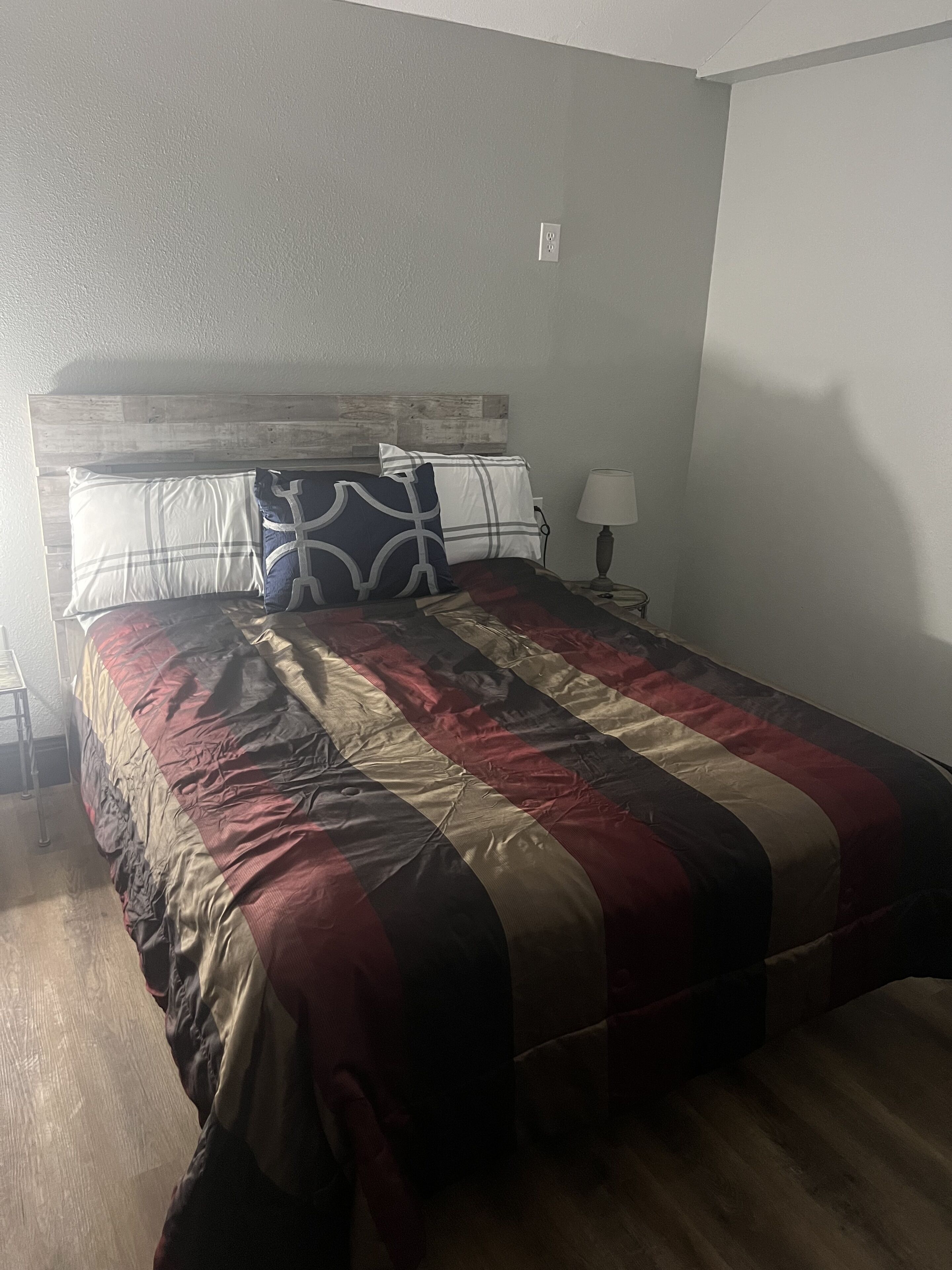 Une chambre à coucher avec un lit, une table de chevet, une lampe et une tête de lit en bois.