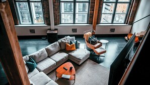 A modern living room with a sectional sofa, a coffee table, and a TV. Large windows provide natural light and views of the city. - Massive Downtown Seattle Loft - Free Parking Included!  (Seattle)