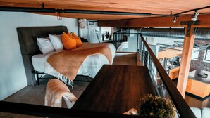 A modern loft-style bedroom with a large bed, a wooden dining table, and a view of the kitchen and living area. - Massive Downtown Seattle Loft - Free Parking Included!  (Seattle)