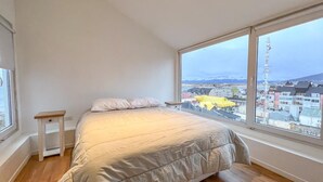 Una camera da letto con un'ampia finestra, un letto e un comodino.