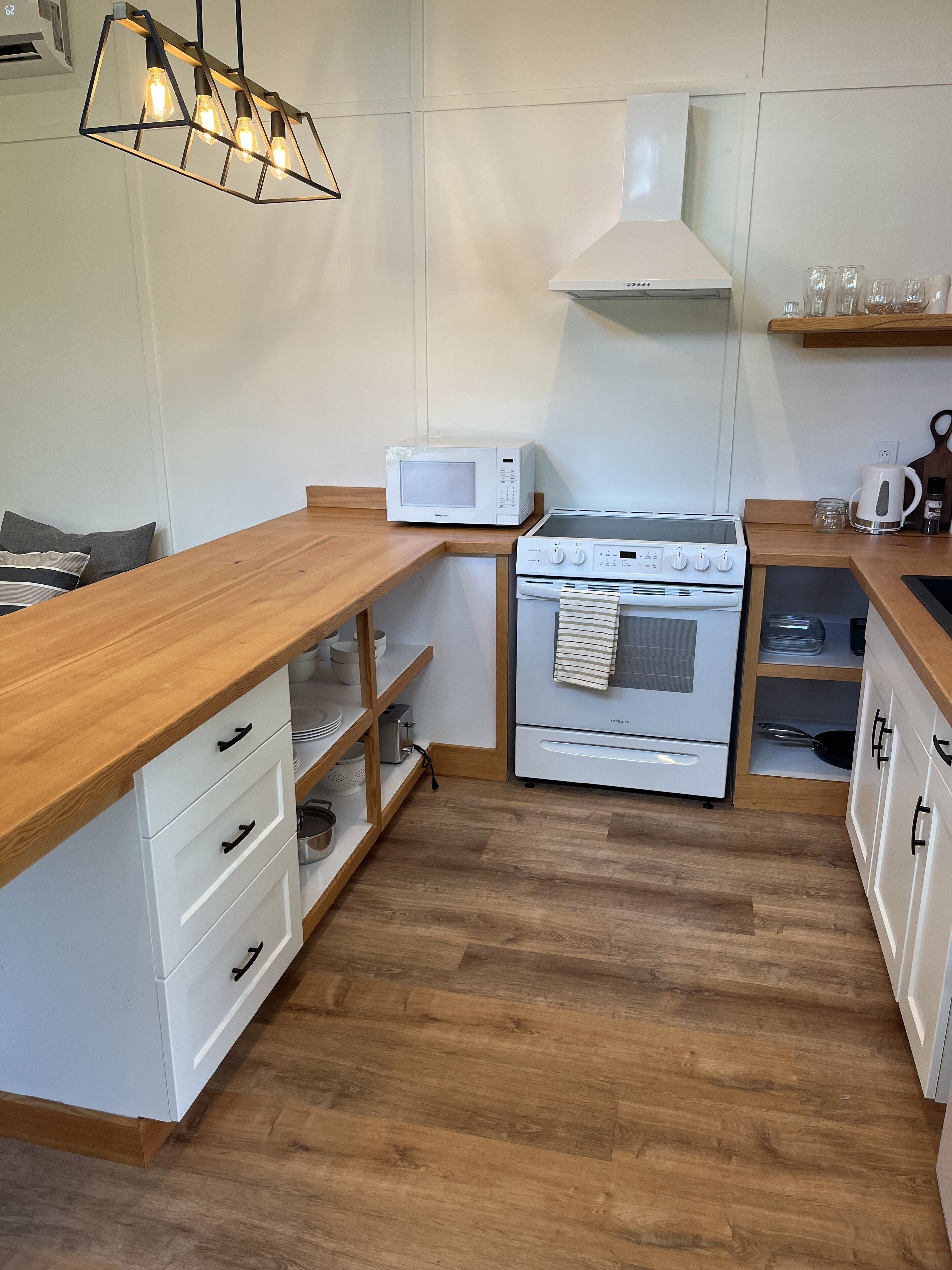 Une cuisine de taille réduite, dotée d’un plan de travail en bois, d’un four à micro-ondes, d’un four et d’une cuisinière.