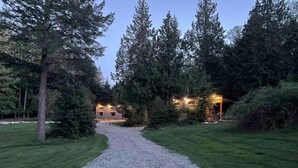Un chemin de gravier mène à un bâtiment entouré d’arbres.