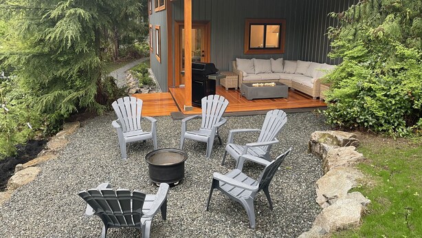 Une cabane moderne dotée d’une terrasse, d’un espace salon extérieur et d’un foyer.