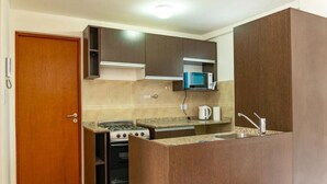A compact kitchen with a stove, microwave, and sink. - Mirador de los Cerros (Ushuaia)