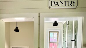 A hallway leading to a pantry area with a door, a window, and a light fixture.