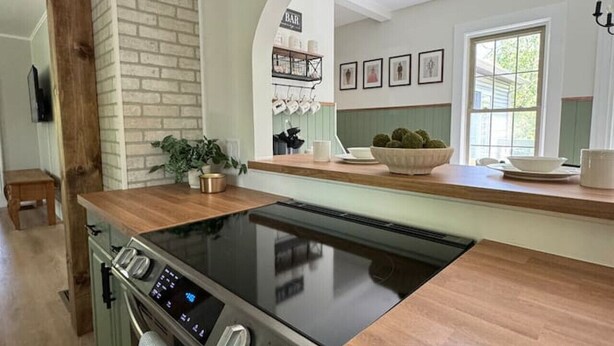 A modern kitchen with a built-in stove, a wooden countertop, and a brick accent wall.