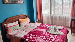 Une chambre à coucher avec un lit, un tableau accroché au mur et une vue par la fenêtre.