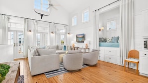 A spacious living room with a sectional sofa, a dining area, and a view of the outdoors. - Windsong 118 BE (Port Aransas)