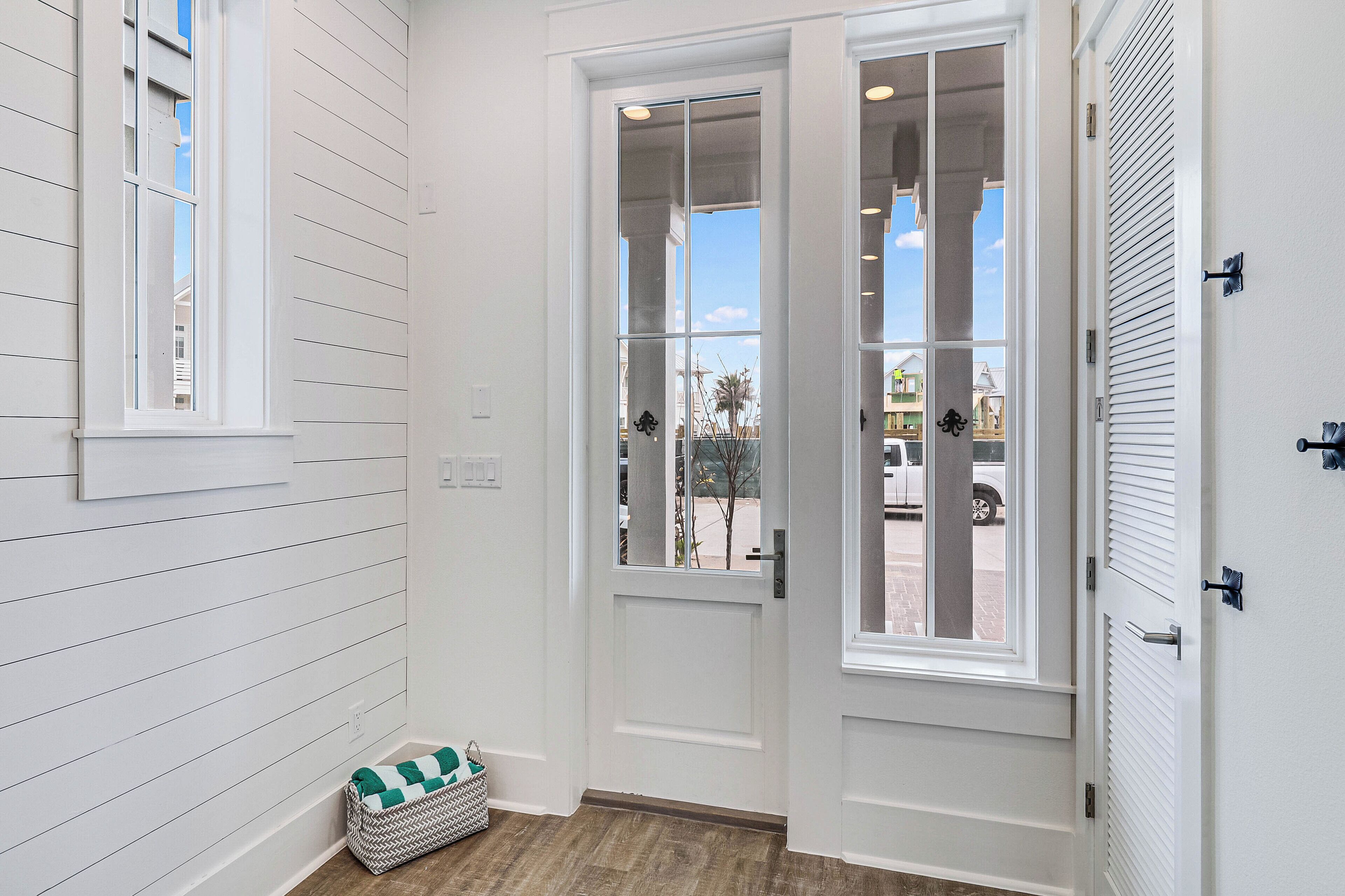 A white door with glass panels, a small basket with a checkered cushion, and a window with horizontal blinds.