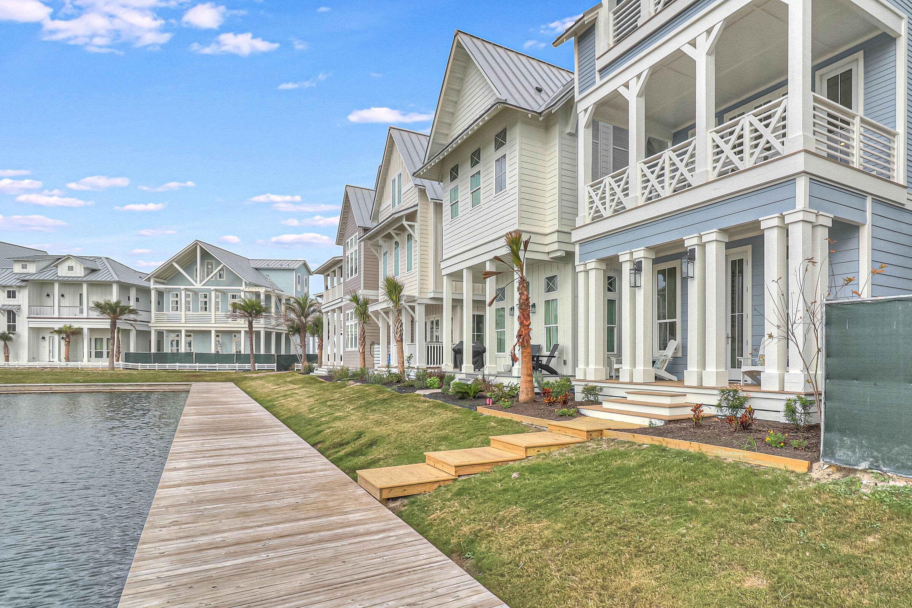 A row of coastal-style houses with a wooden boardwalk leading to a swimming pool.