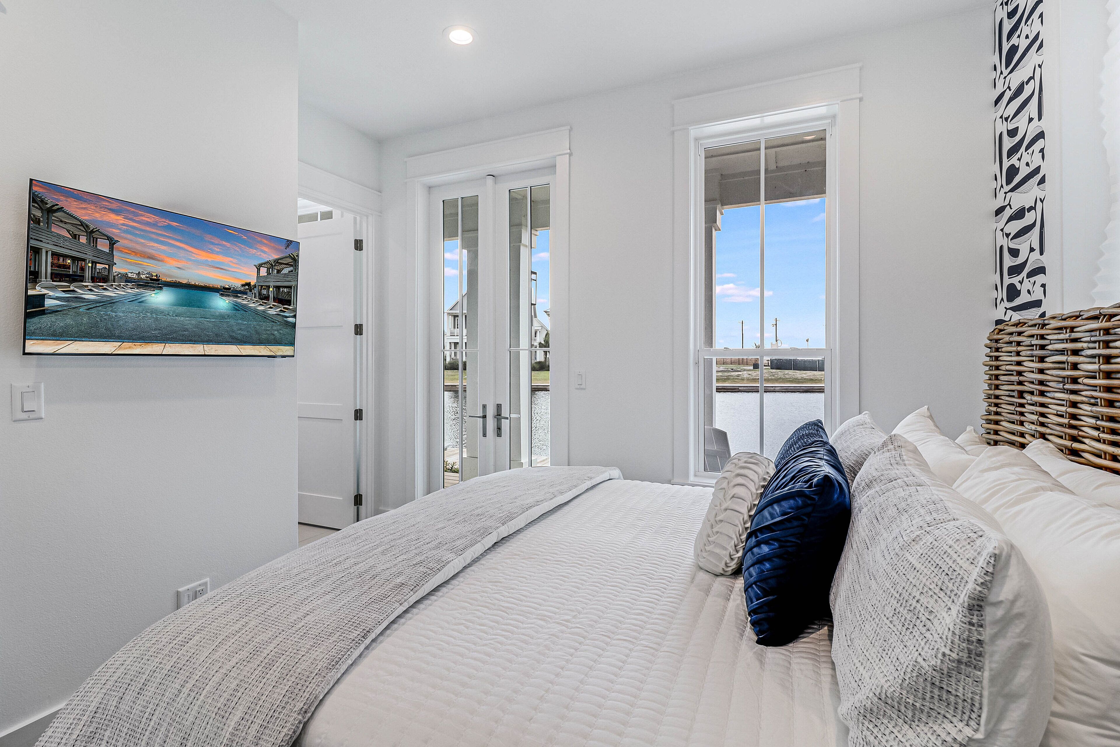 A bedroom with a large bed, a view through a glass door, and a painting on the wall.