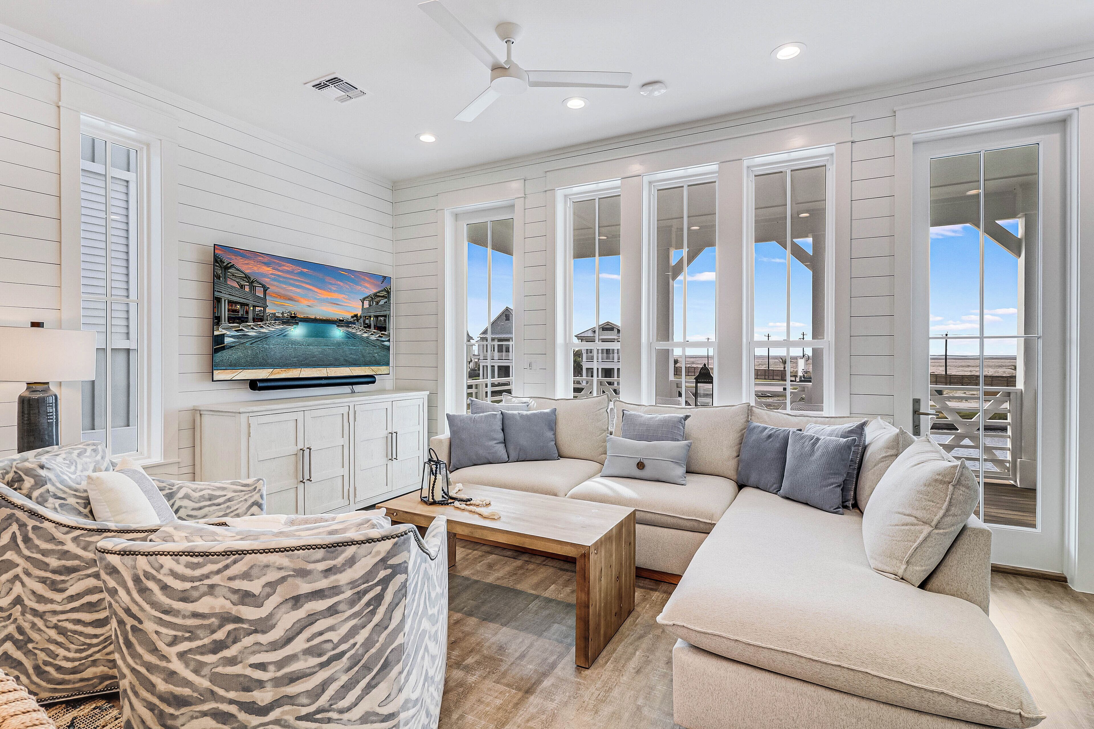 A spacious living room with a large sofa, a coffee table, and a television mounted on the wall.