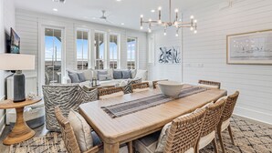A spacious dining area with a wooden table, wicker chairs, and a chandelier. - Sea Vous Play 112 NEI (Port Aransas)