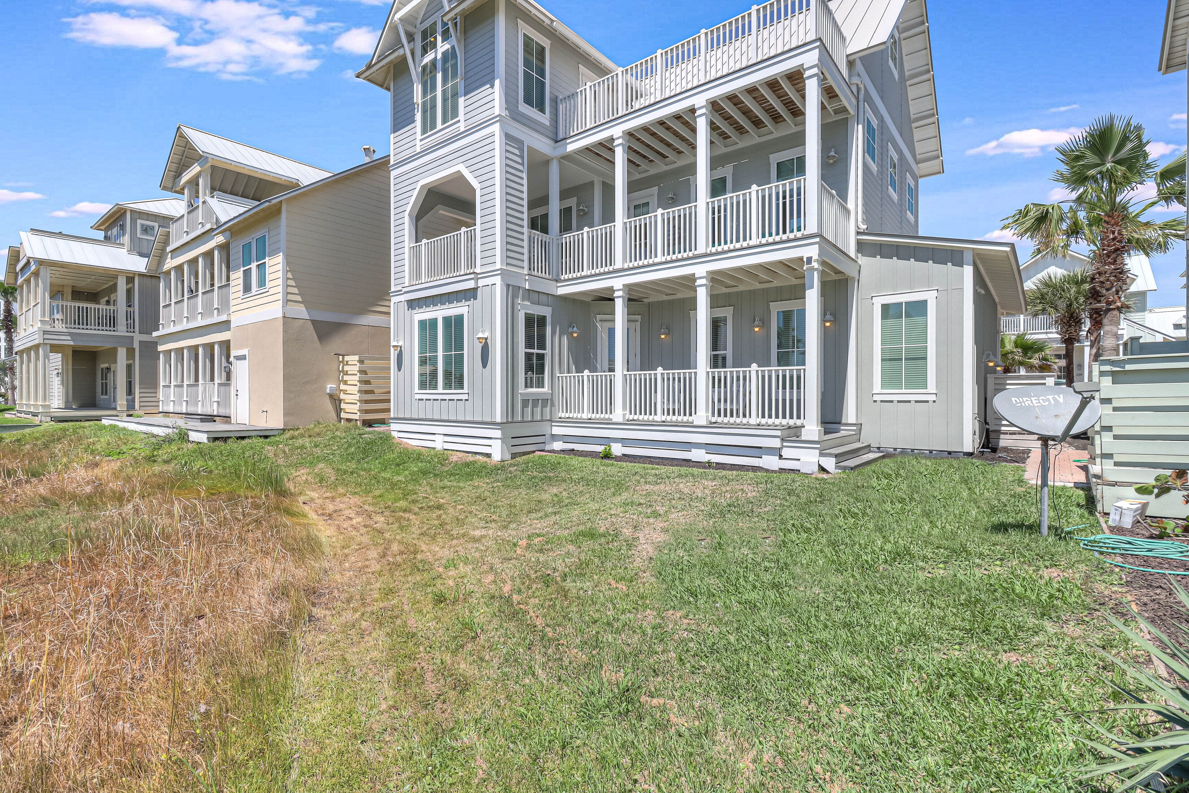 A multi-story residential building with balconies and a grassy front yard.