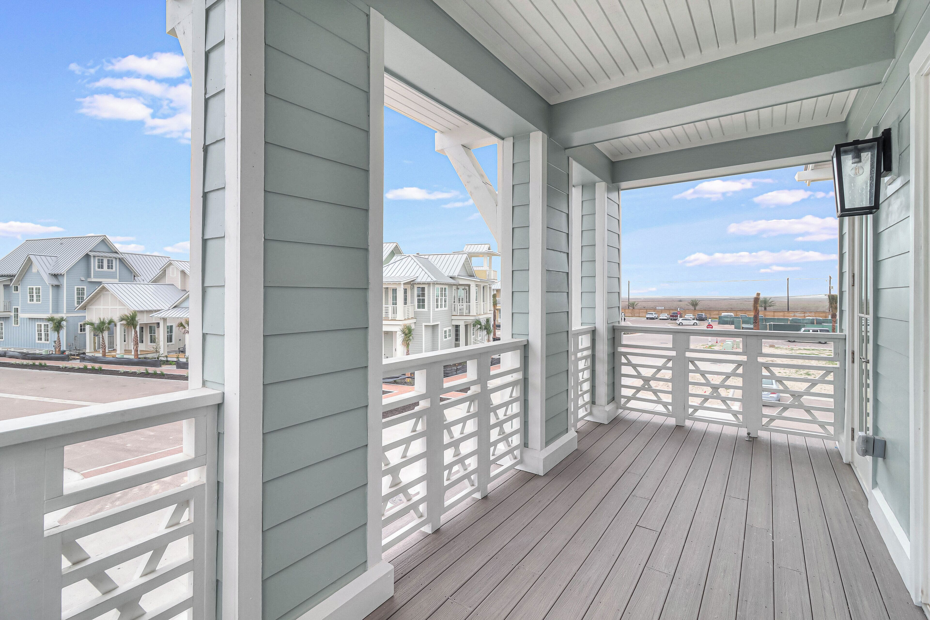A covered porch with a view of neighboring houses and a clear sky.