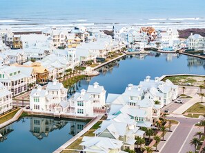 A coastal residential area with houses along a waterway, featuring a dock and a small boat. - Easy Breezy 225 TEA (Port Aransas)