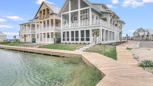 A large, multi-story house with a prominent balcony, a wooden deck, and a small water feature.