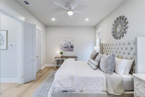A bedroom with a bed, bedside tables, a desk, and a ceiling fan. - Easy Breezy 225 TEA (Port Aransas)