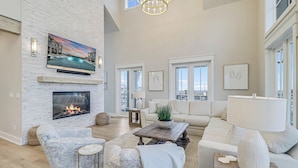 A spacious living room with a fireplace, comfortable seating, and large windows.