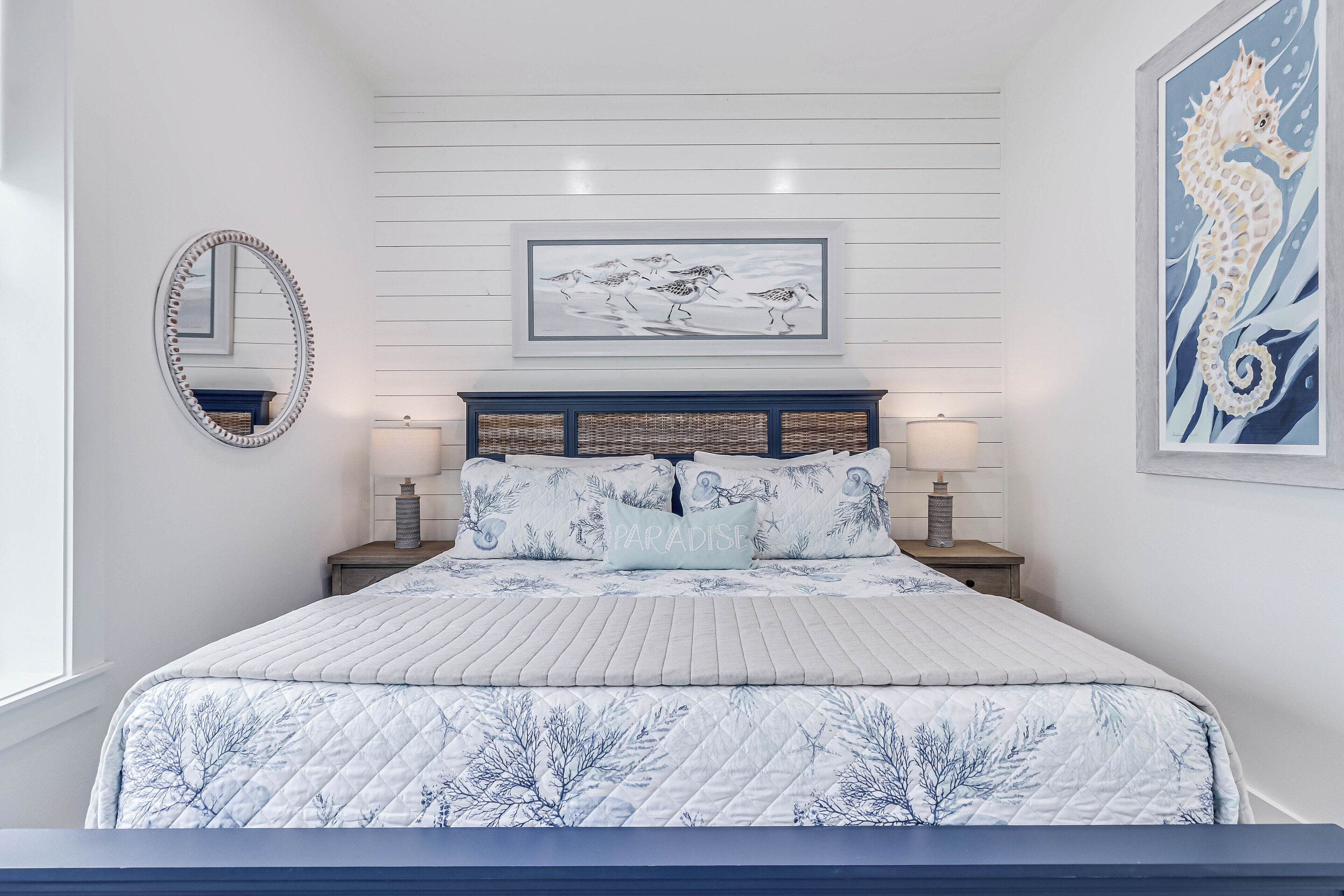 Quarto com cama, espelho, quadro emoldurado e mesa de cabeceira.